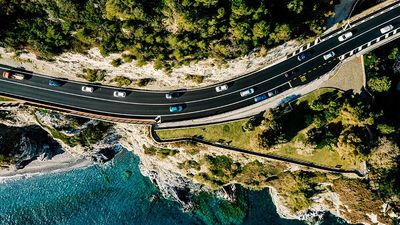 Aerial view of road going along the mountain and ocean or sea. Drone photography from above