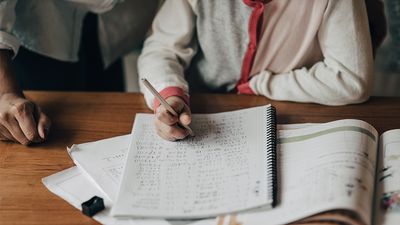 Close up of child's hands doing math homework. Mother helping her daughter doing math homework. Student girl schoolwork. parent child