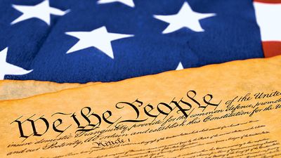 United State Constitution lying on the United State flag set-up shot (We the People, democracy, stars and stripes).