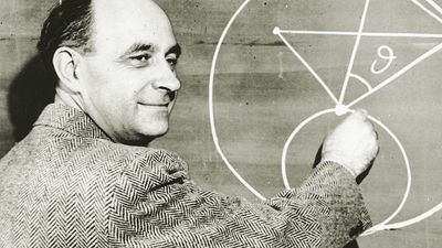 Italian-born physicist Dr. Enrico Fermi draws a diagram at a blackboard with mathematical equations. circa 1950.