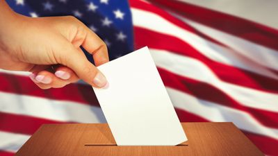 Close up of a hand placing a ballot in a ballot box. Election vote voter voting