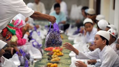 Indonesian Muslim children receive a bag of goods before Iftar meal or the breaking of the fast consisting of fruit, rice cakes, doughnuts, tea and water that comes with gifts for the children at Darussalam mosque in central Jakarta on September 5, 2010 as Muslims worldwide prepare for festivities marking the end of the fasting month of Ramadan and ushering the Eid al-Fitr festival. Indonesia is the world's most populous Muslim majority country.