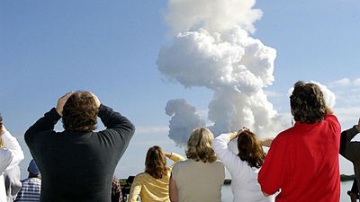 After a perfect launch, spectators try to catch a last glimpse of Space Shuttle Columbia, barely visible at the top end of the twisted column of smoke.