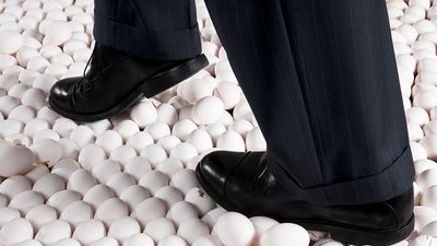 Man in Suit Walking on Eggshells. Idiom egg shell figure of speech