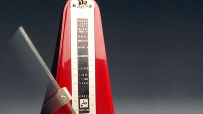 Metronome. Music. Tempo. Rhythm. Beats. Ticks.  Red metronome with swinging pendulum.