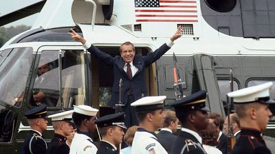 President Richard M. Nixon smiles and gives the victory sign as he boards the White House helicopter after his resignation on August 9, 1974 in Washington, D.C.