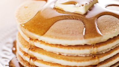 Stack of pancakes on a plate with butter and maple syrup (breakfast, flapjacks, hotcakes).