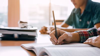 Close up of students hands writing in notebooks. Homework study school classroom high school