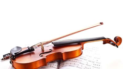 Violin on top of sheet music. (musical instrument)